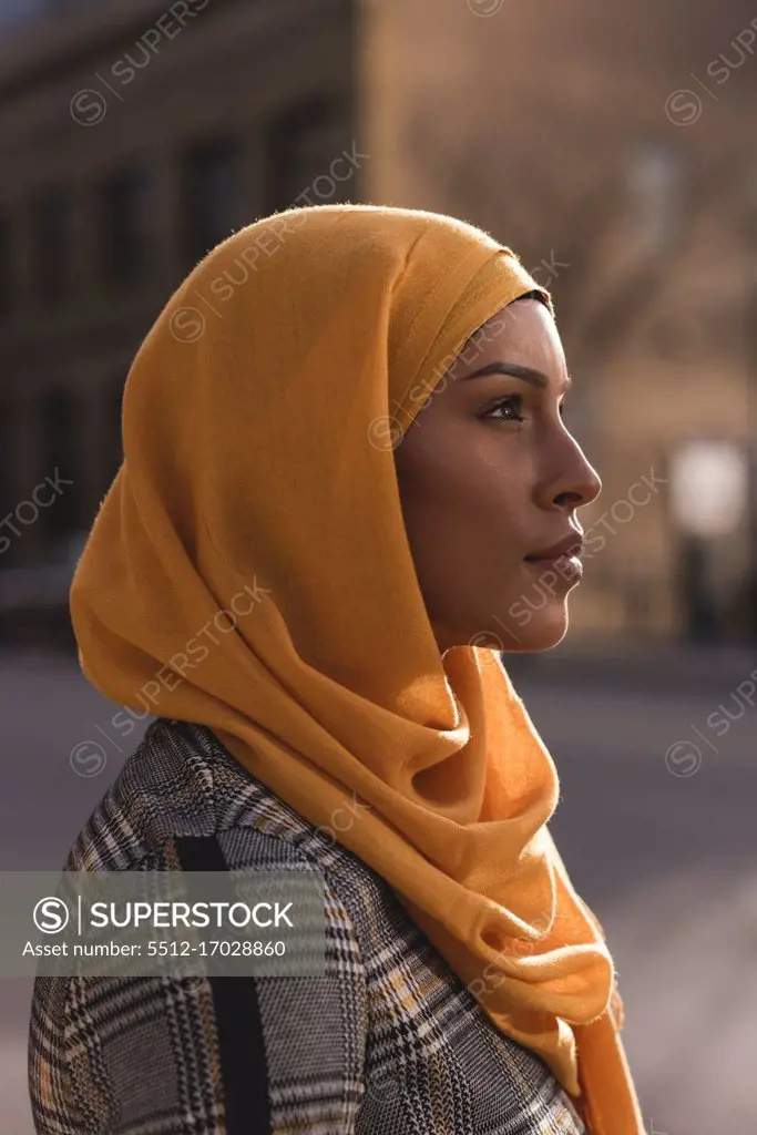 Thoughtful hijab woman standing in city