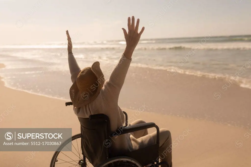 Rear view of active disabled senior woman with arms up on the beach