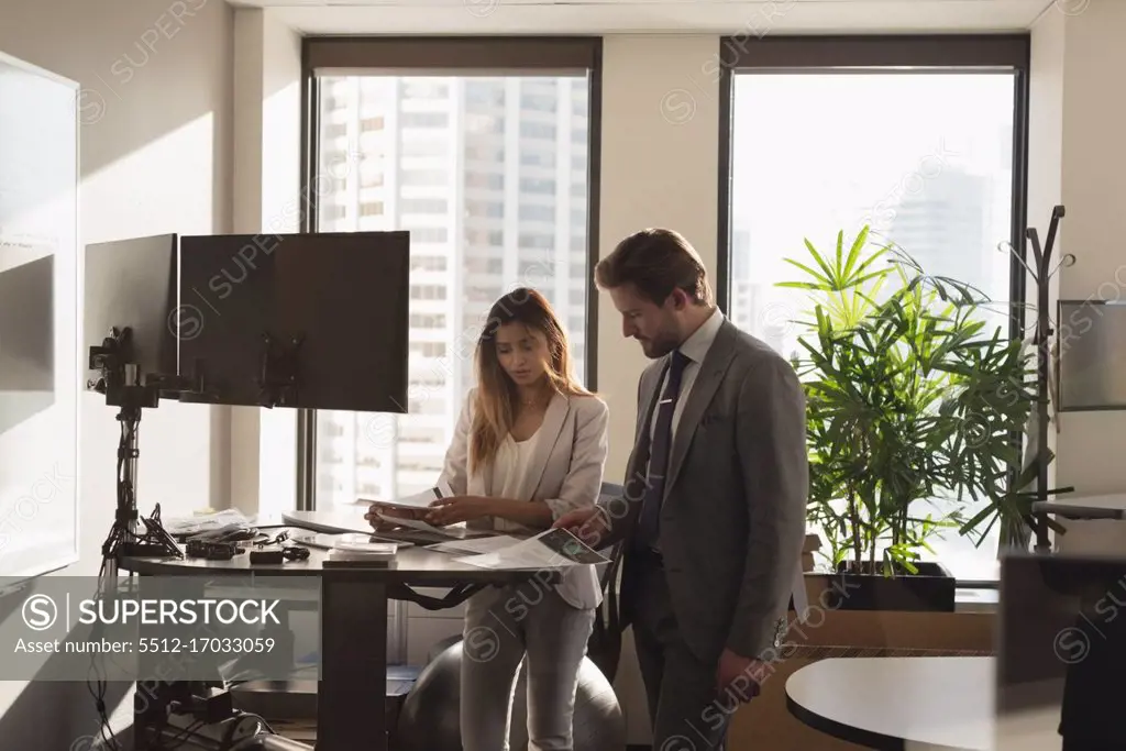 Side view of Standing business people discussing over documents in the modern office