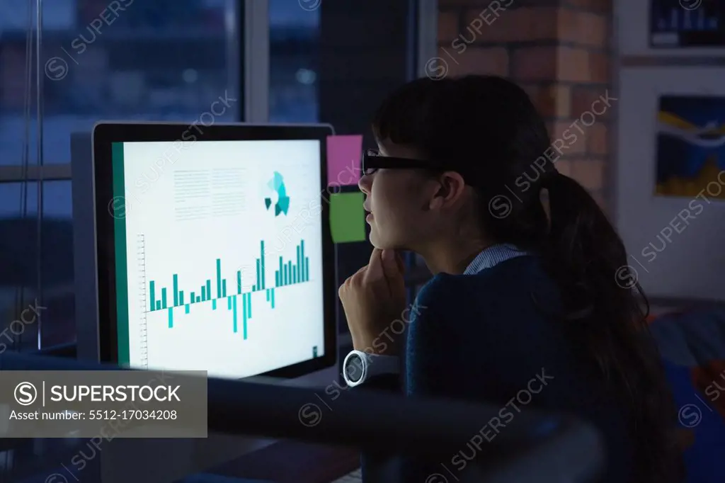 Side view of caucasian  businesswoman working over graph project in office at desk by night