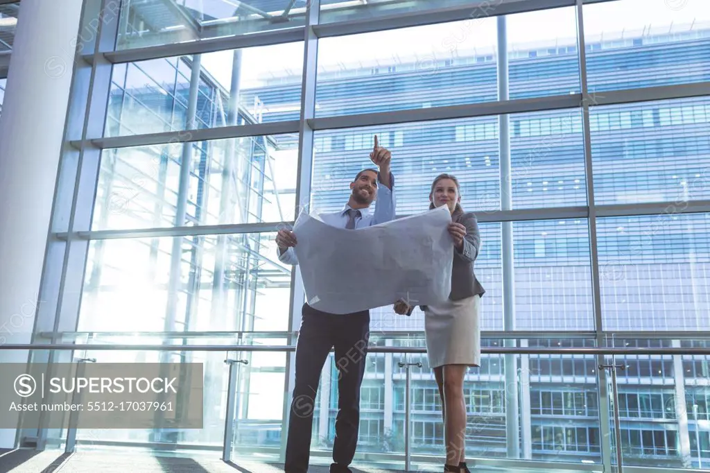 Low angle view of business people discussing over blueprint in a modern office building