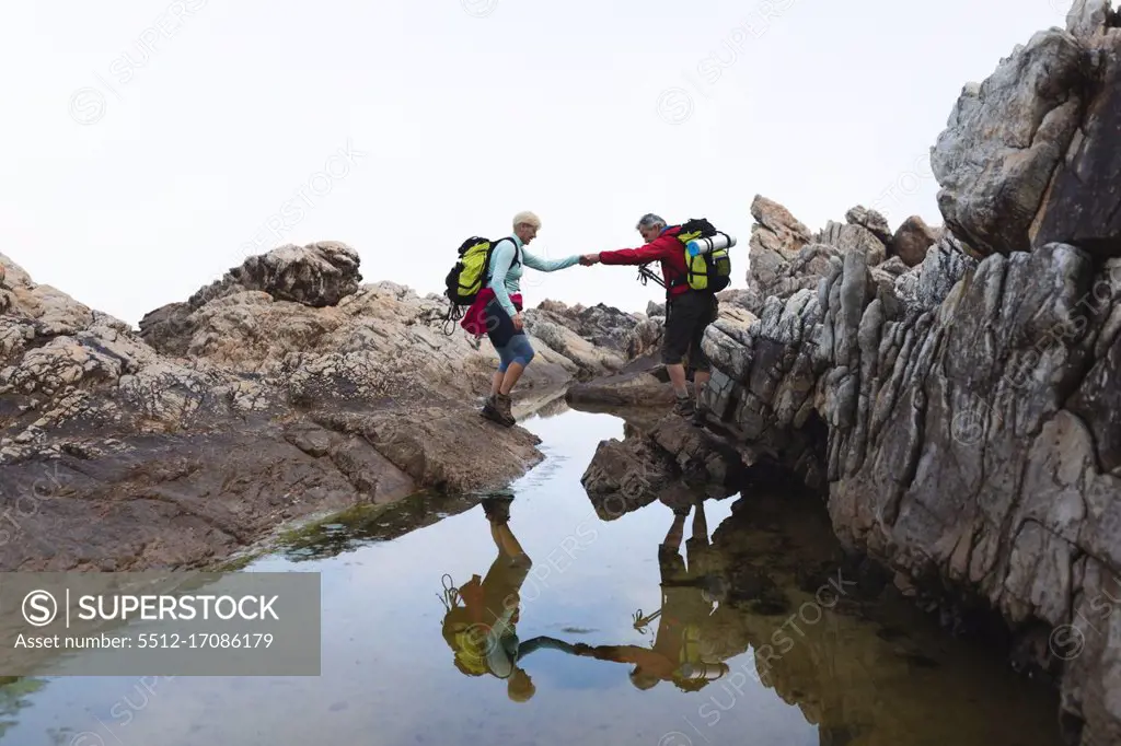 Senior couple spending time in nature together, walking in the mountains, holding hands. healthy lifestyle retirement activity.