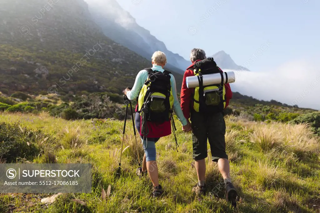 Senior couple spending time in nature together, walking in the mountains, holding hands. healthy lifestyle retirement activity.