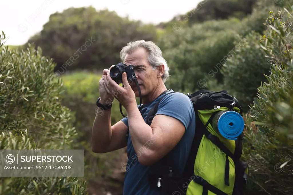 Senior man spending time in nature, walking in the mountains, taking a picture. healthy lifestyle retirement activity.