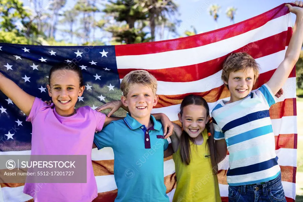 Portrait of children holding american flag in park