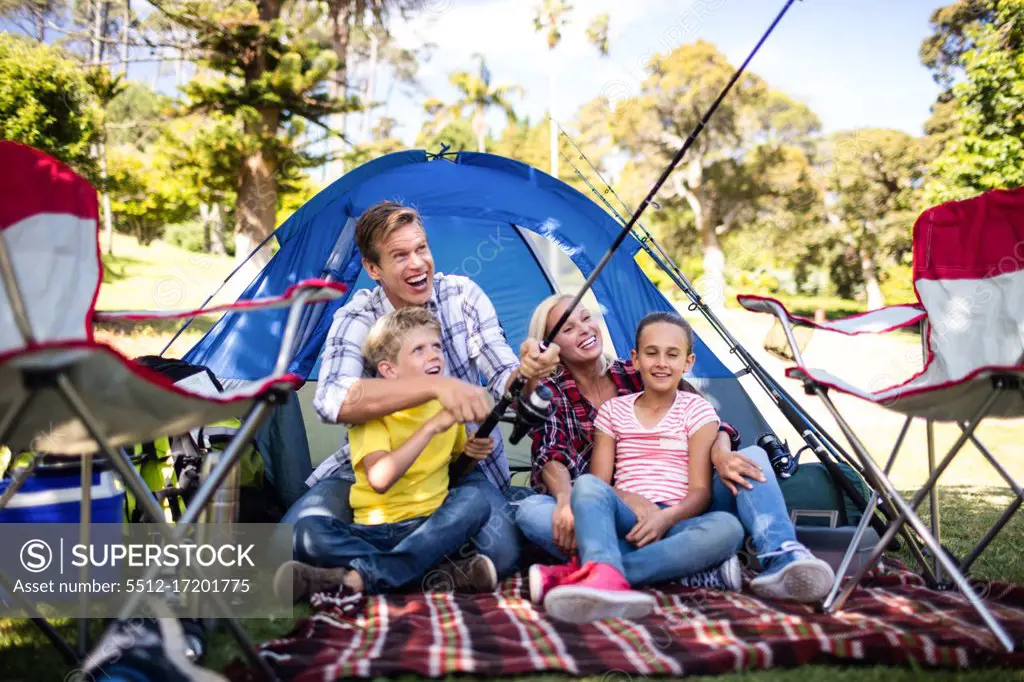 Family on a camping trip fishing outside their tent