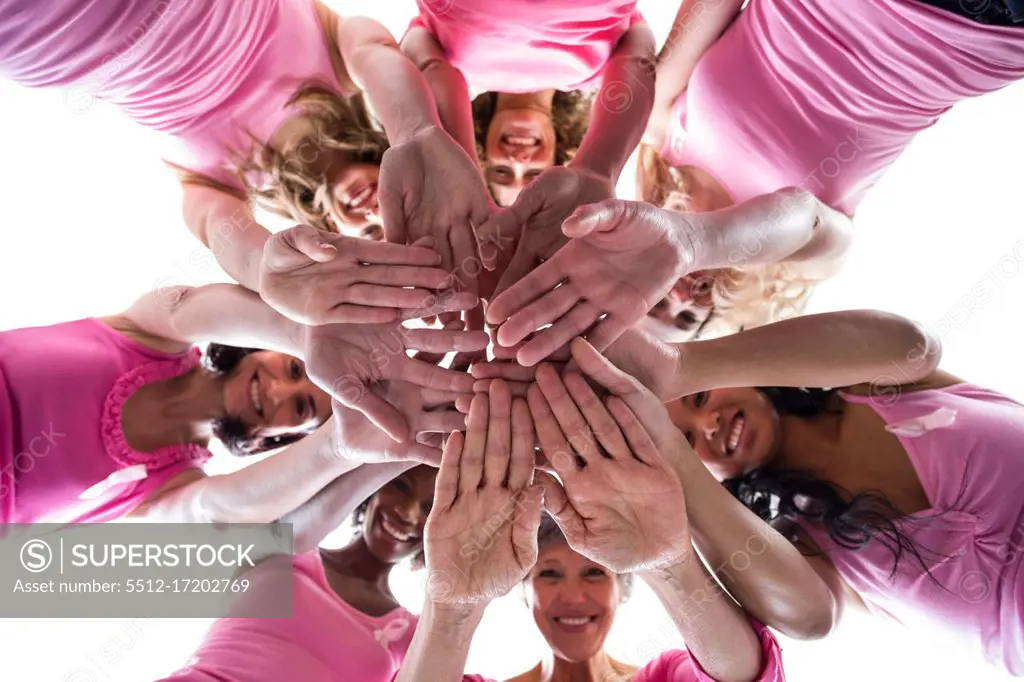 Women in pink outfits joining in a circle on white background for breast cancer awareness 