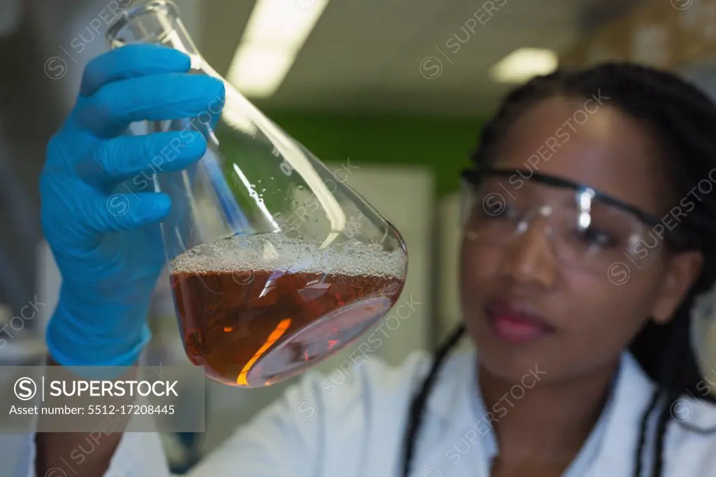 Scientist checking a solution in conical flask at lab