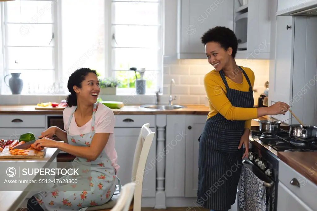 Mixed race lesbian couple preparing food in kitchen. self isolation quality family time at home together during coronavirus covid 19 pandemic.
