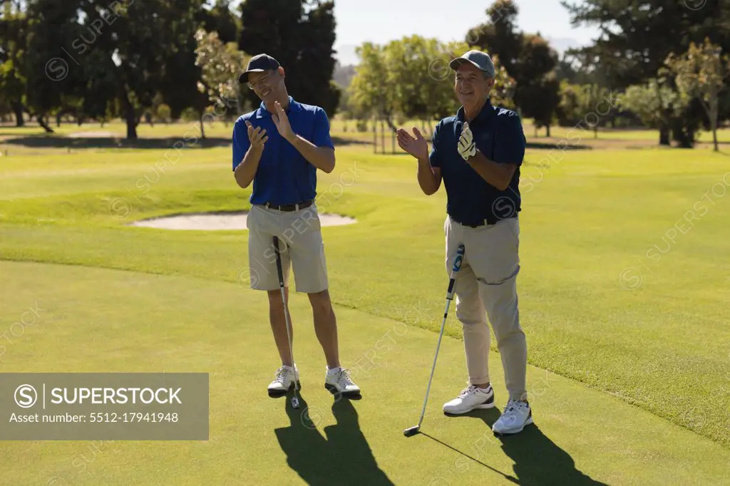 Two caucasian senior men holding golf clubs and clapping. golf sports hobby, healthy retirement lifestyle