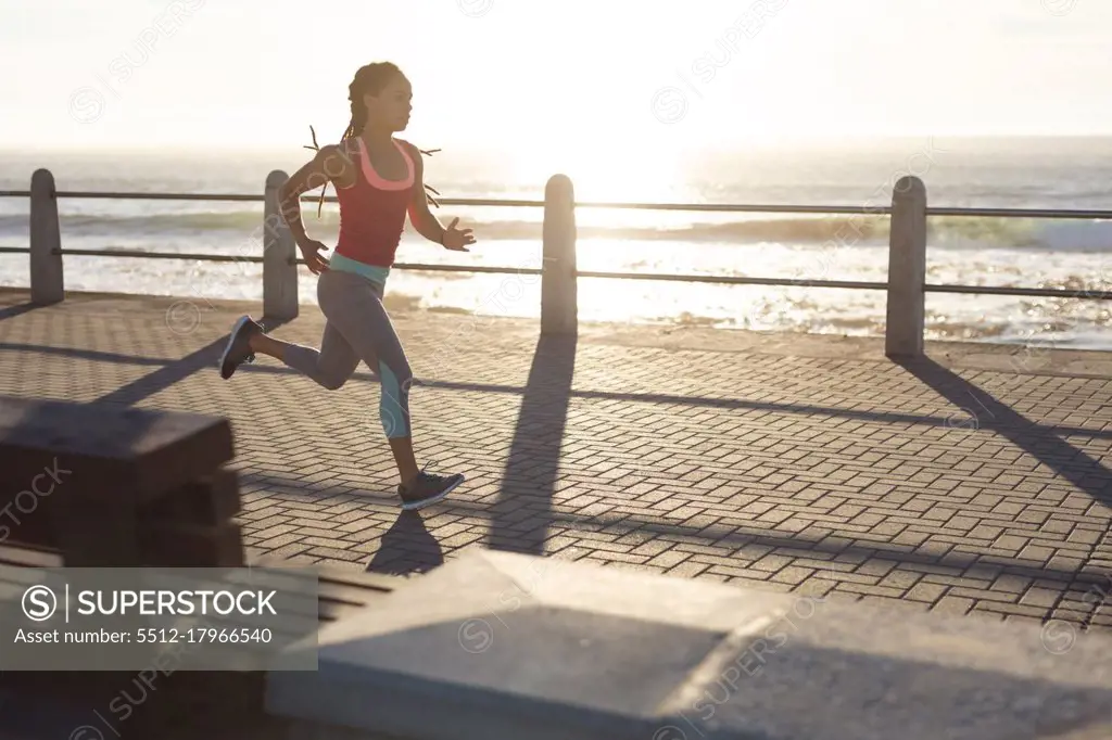 African american woman exercising on a promenade by the sea jogging. fitness healthy outdoor lifestyle.