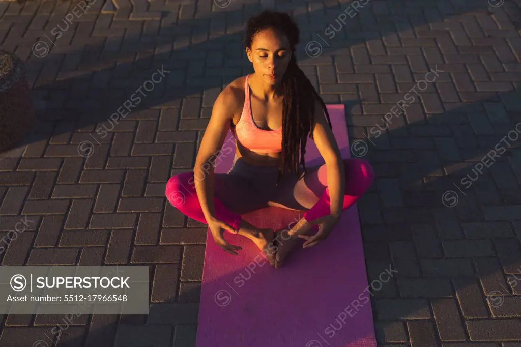 African american woman exercising on promenade by the sea doing yoga. fitness healthy outdoor lifestyle.