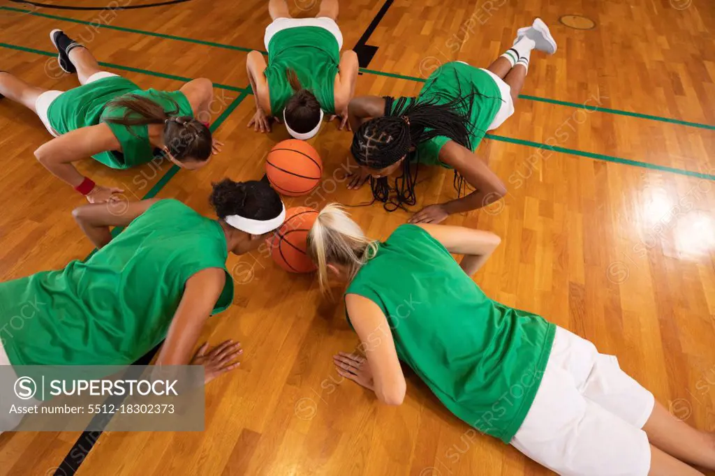 Diverse female basketball team wearing sportswear and doing push ups. basketball, sports training at an indoor court.