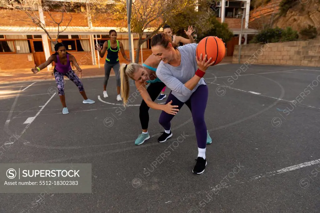 Diverse female basketball team wearing sportswear and practice dribbling ball. basketball, sports training at an outdoor urban court.