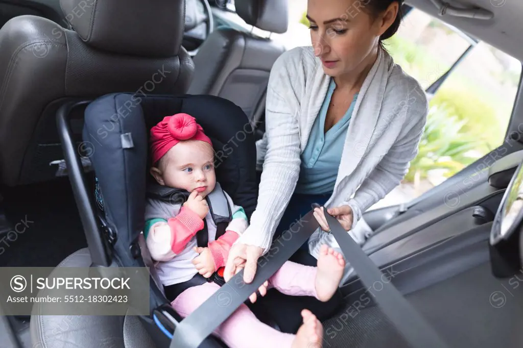 Caucasian mother putting her baby in safety baby seat in the car. motherhood, love and baby care concept