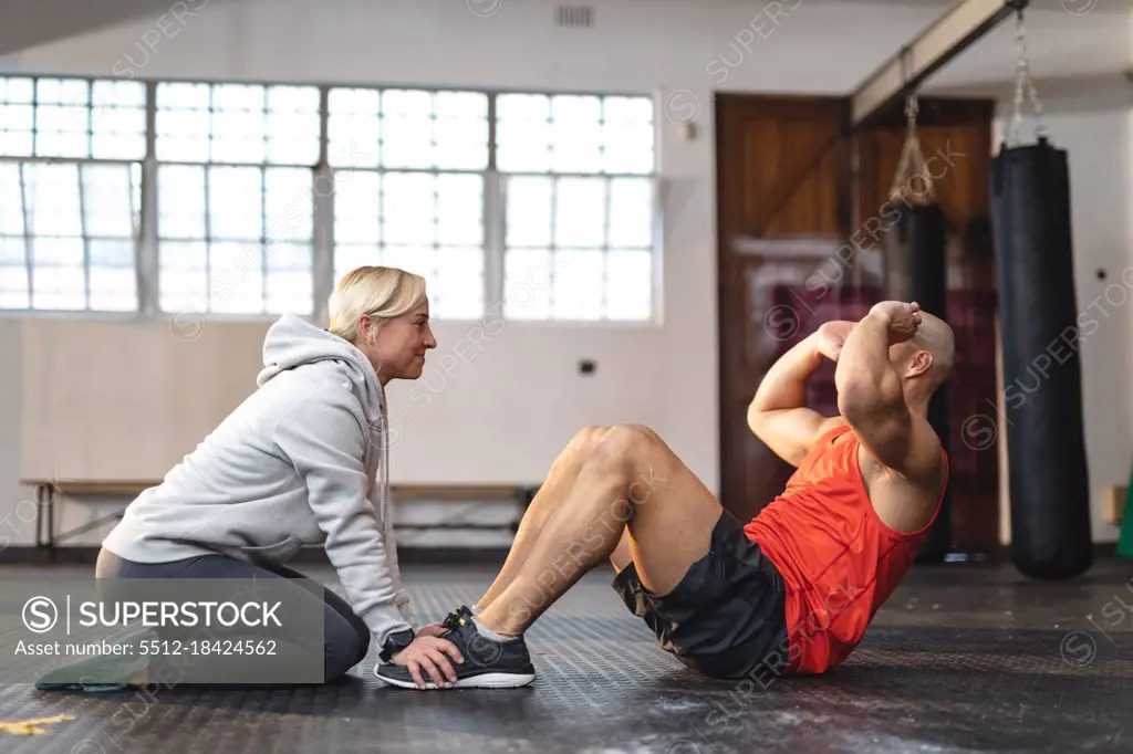 Caucasian female trainer instructing man exercising at gym doing