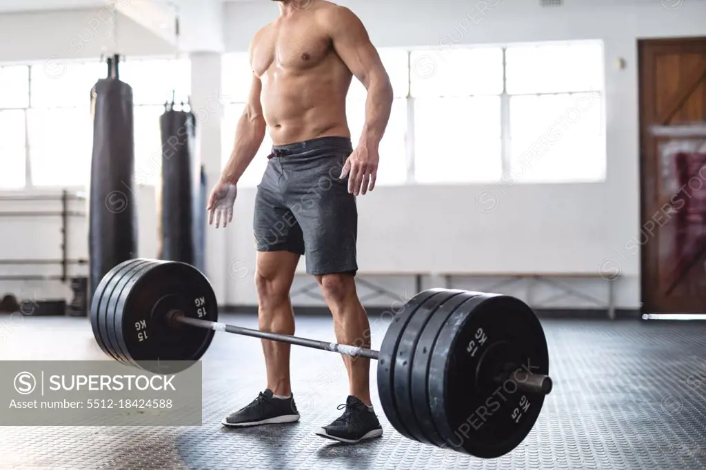 Strong caucasian man exercising at gym, lifting weights. strength and fitness cross training for boxing.