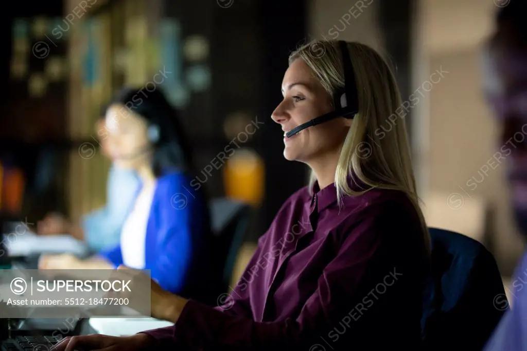 Caucasian businesswoman working at night wearing headset. working late in business at a modern office.