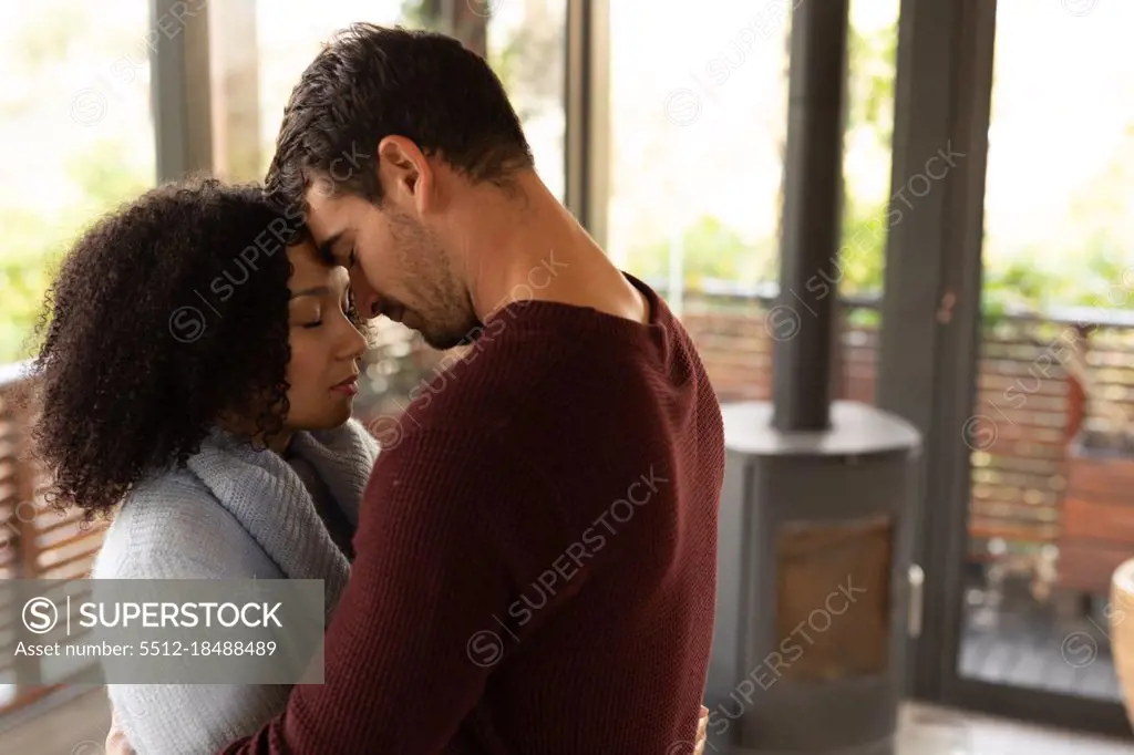 Happy diverse couple in living room embracing with eyes closed. spending time off at home in modern apartment.