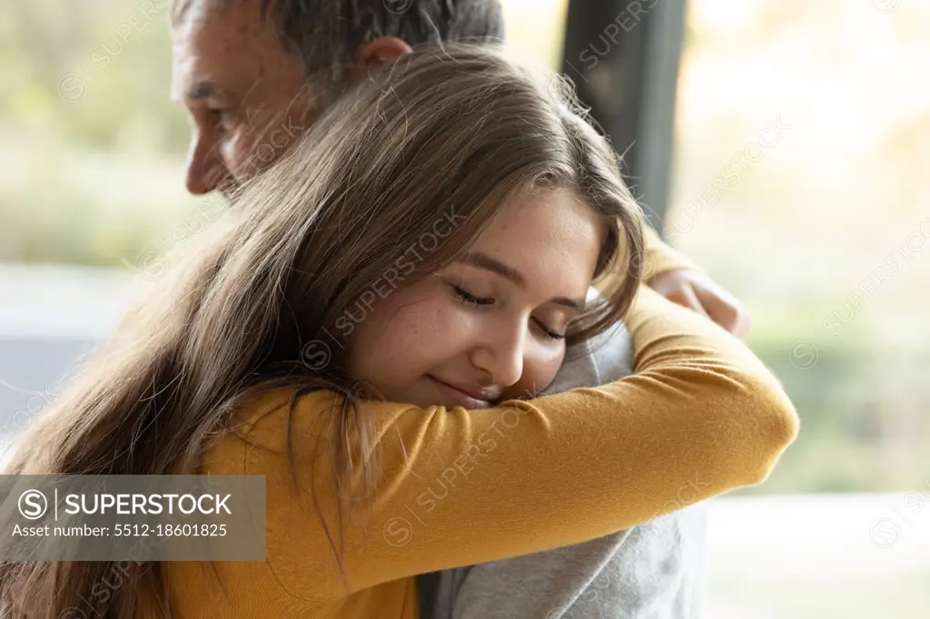 Happy caucasian grandfather and granddaughter hugging at home. family time, active and healthy retirement lifestyle at home.