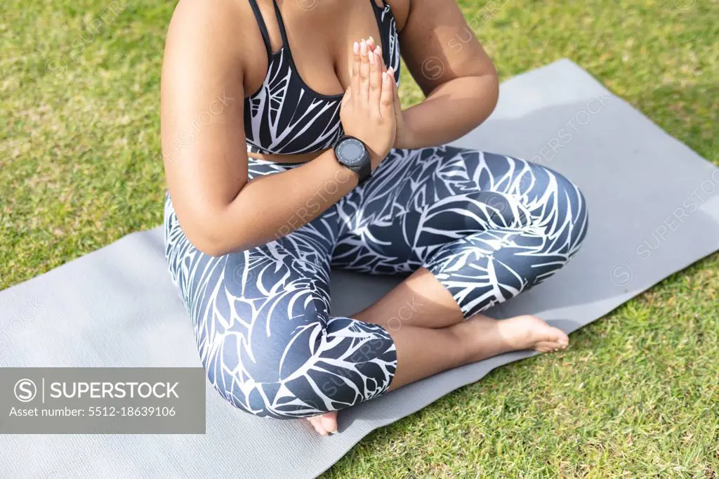 Midsection of african american plus size woman practicing yoga on mat in  garden. fitness and healthy, active lifestyle. - SuperStock