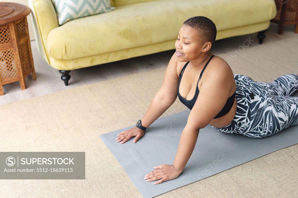 Young plus size woman in sporty top and leggings standing in plank on yoga  mat spending time on green grass in yard. Black kitten walks around her.  Well being and fitness concept 17772580 Stock Photo at Vecteezy