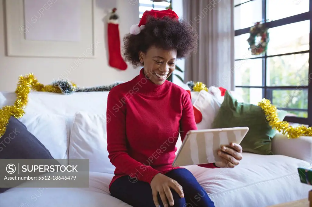 Happy african american woman in santa hat making tablet christmas video call. christmas, festivity and communication technology.