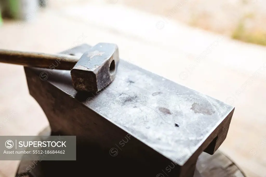 Close-up of hammer with wooden handle on anvil in manufacturing industry. forging, metalwork and manufacturing industry.