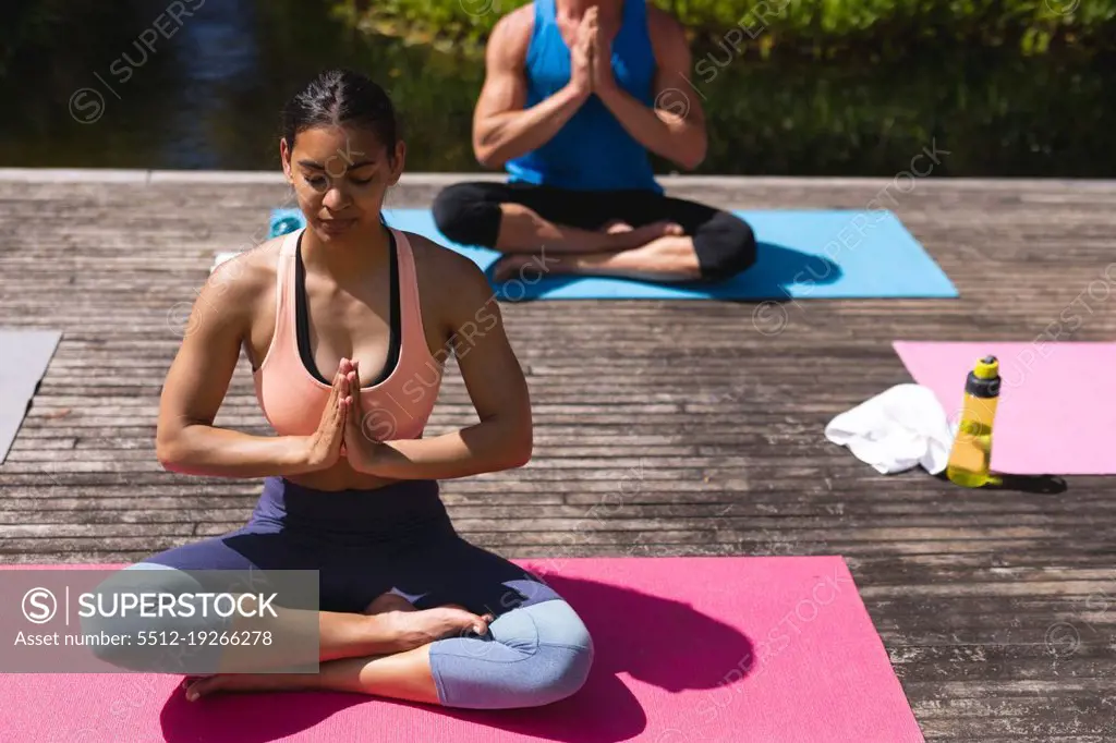 Young woman meditating while sitting with cross-legged and hands clasped on exercise mat. yoga, healthy lifestyle and body care.