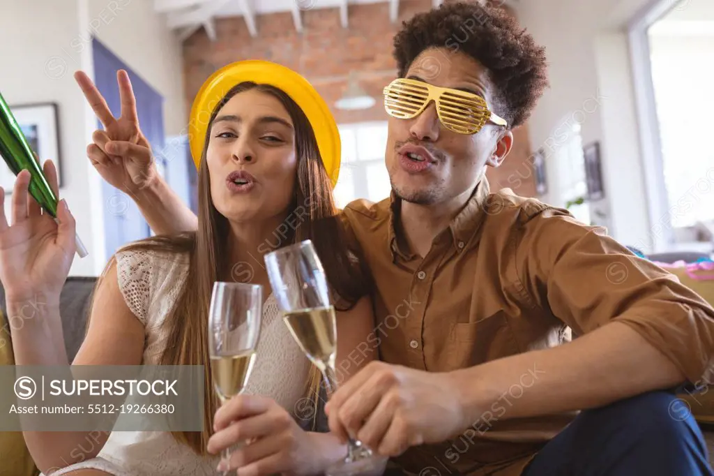 Portrait of happy biracial couple enjoying party with champagne flutes at home. celebration and lifestyle.