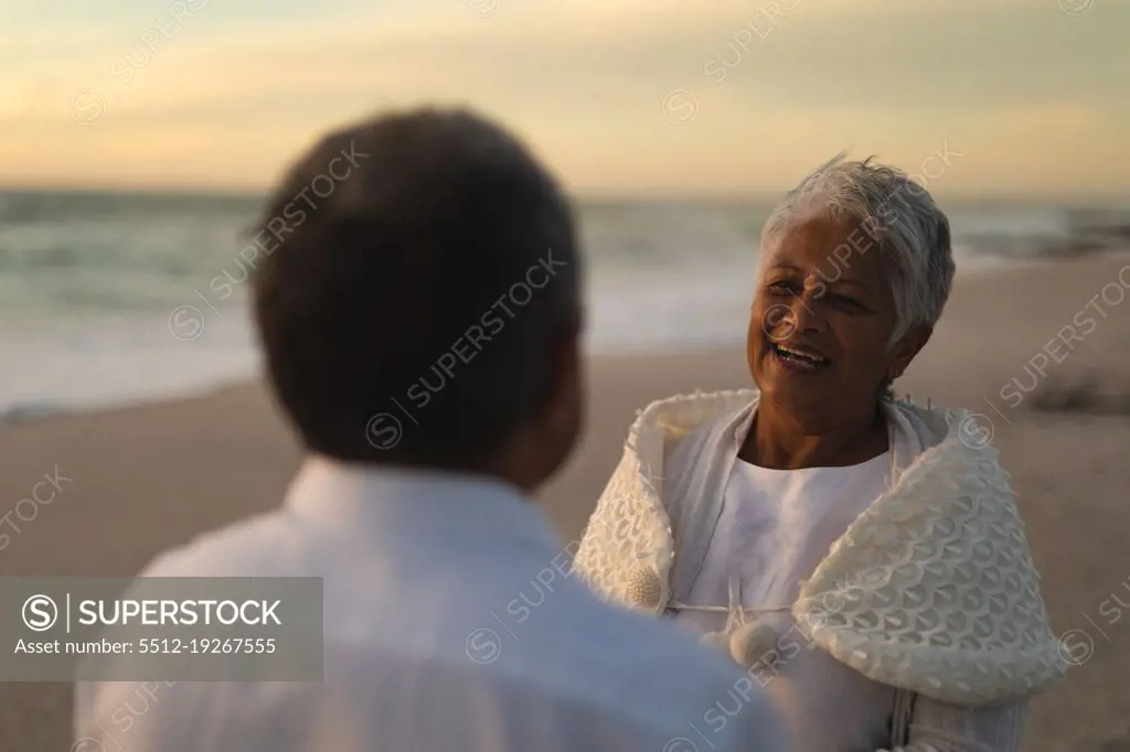 Happy biracial senior woman looking man during wedding ceremony at beach. wedding ceremony, lifestyle and love.