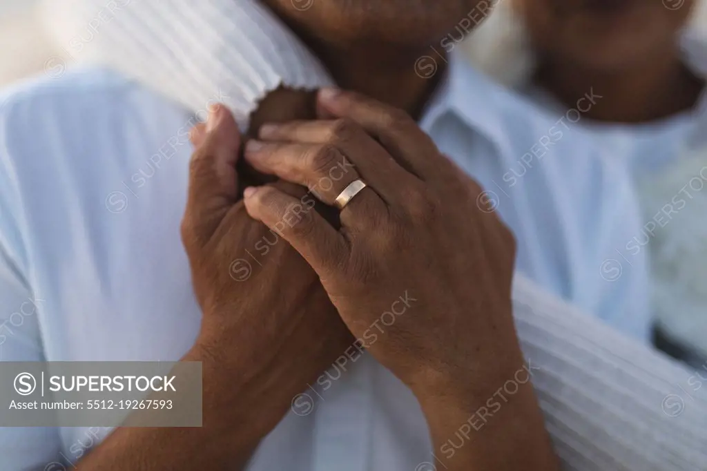 Midsection of senior biracial woman embracing man from behind with wedding ring during sunset. lifestyle, love and weekend.