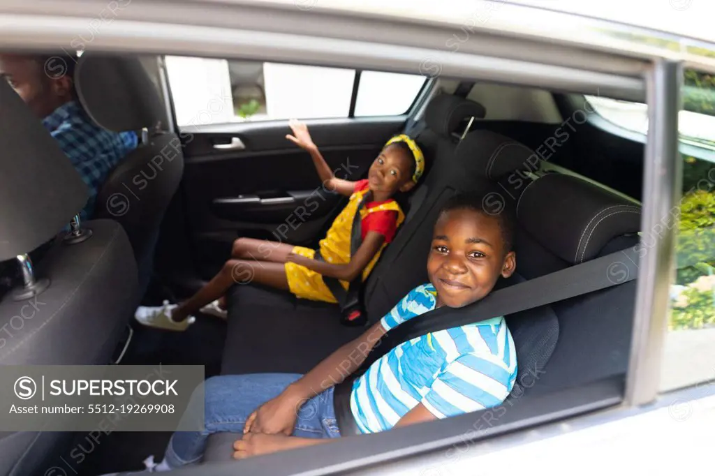 Portrait of smiling african american brother and sister with seat belts traveling in car. unaltered, family, childhood, safety, weekend and travel concept.