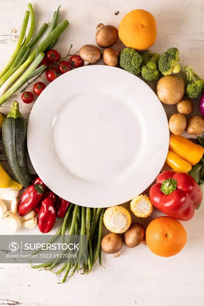 Directly above shot of empty white plate amidst various vegetables and fruits on table. unaltered, vegetable, healthy food, raw food, fruit, variation and organic concept.