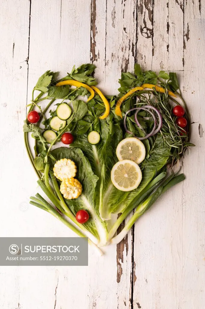 Overhead view of fresh green vegetables arranged as heart shape on white wooden table. unaltered, food, healthy eating, organic concept.