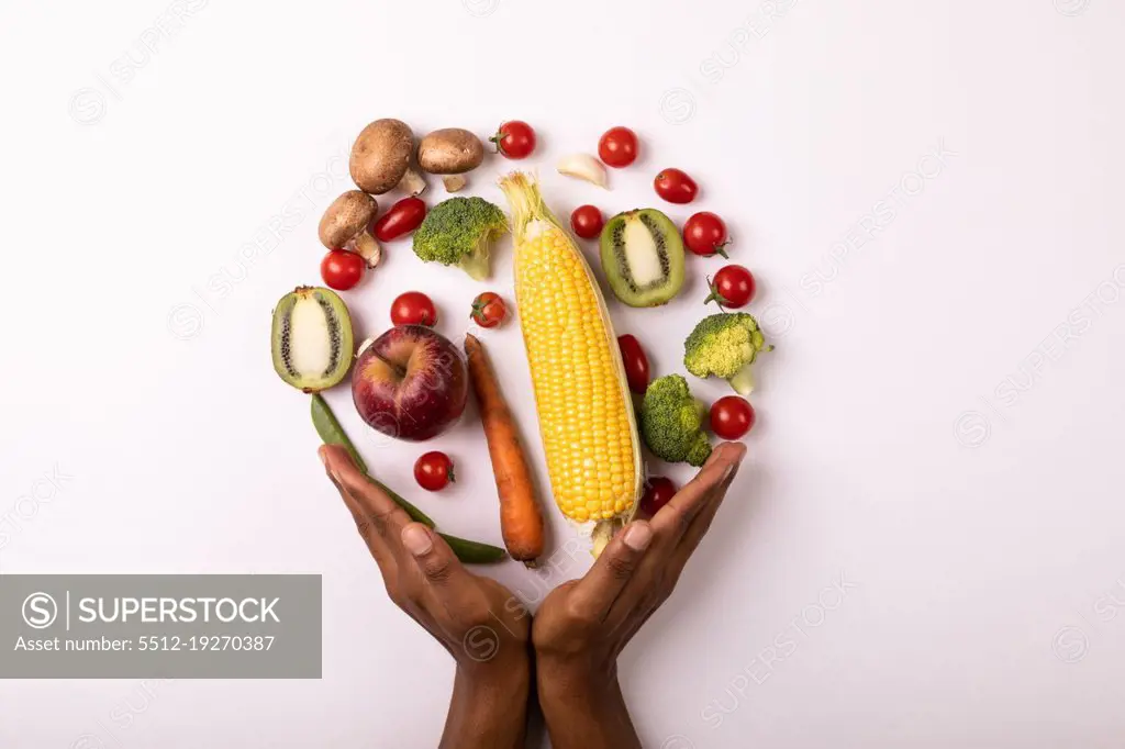 Cropped hands by vegetables and fruits arranged in circle by copy space on white background. unaltered, food, healthy eating, organic concept.