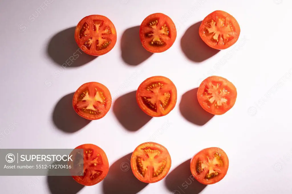 Directly above view of fresh red tomato halves arranged in a row on white background. unaltered, food, healthy eating, organic concept.