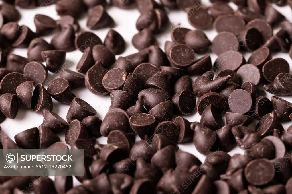 Close-up full frame shot of fresh chocolate chips on white background. unaltered, sweet food and unhealthy eating concept.