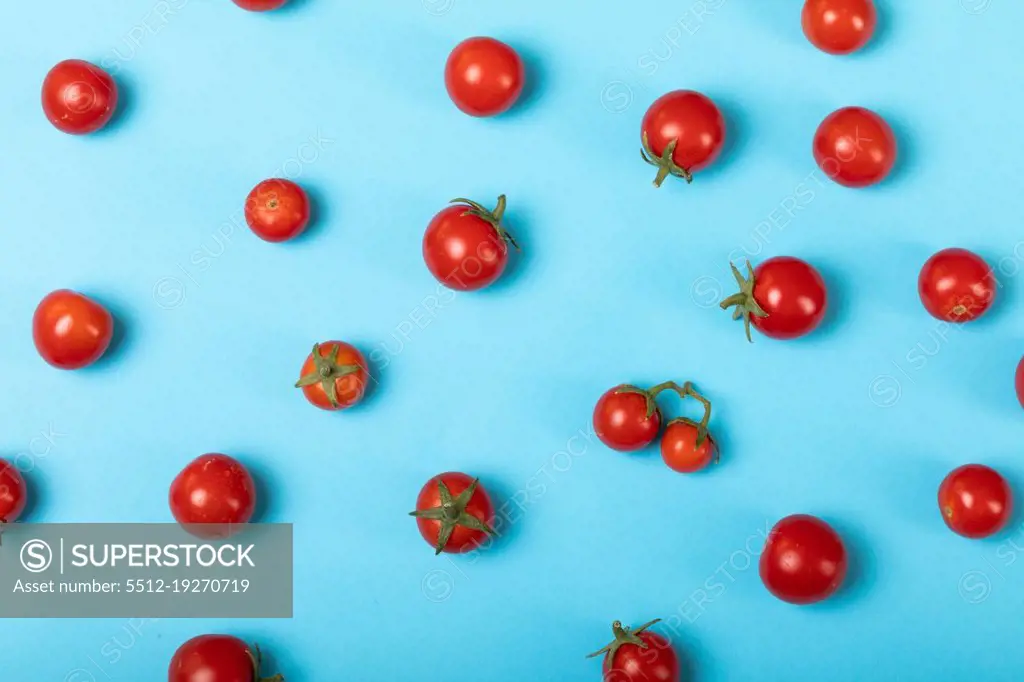 Directly above view of fresh red tomatoes scattered over blue background. unaltered, organic food and healthy eating concept.