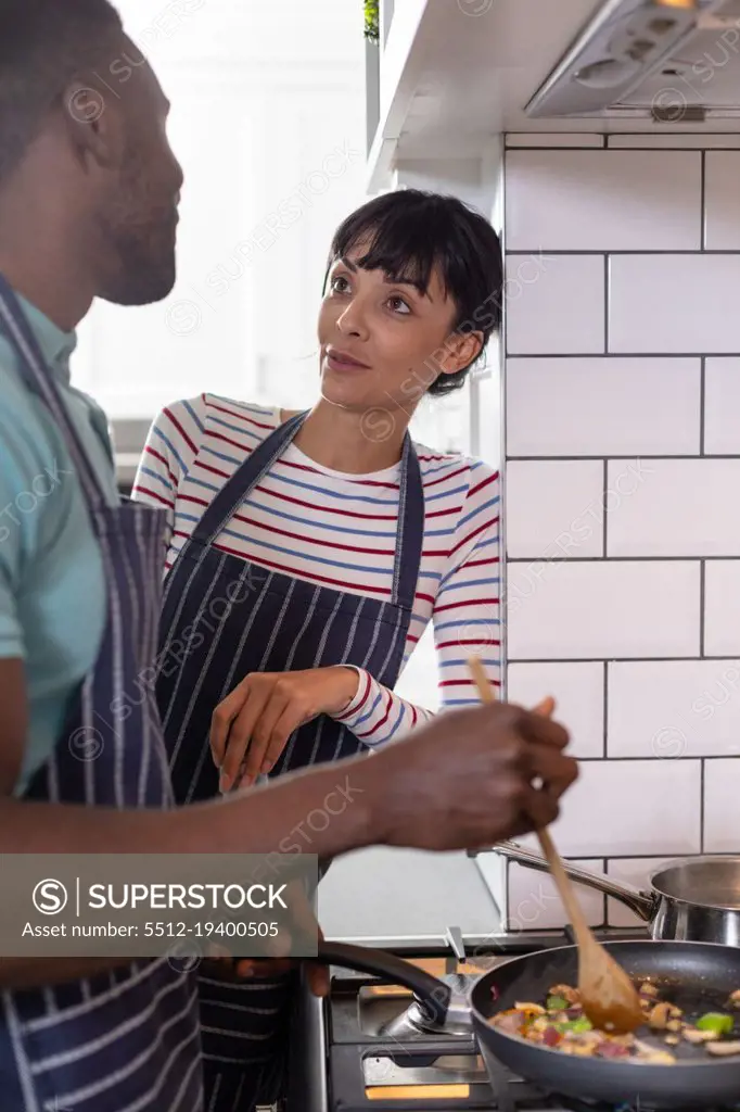 Multiracial young couple cooking food together at home. unaltered, lifestyle, togetherness, preparing food, love, domestic life, food.