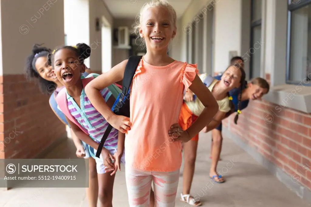 Portrait of smiling playful multiracial elementary school students standing in row at school. unaltered, education, childhood, together and school concept.