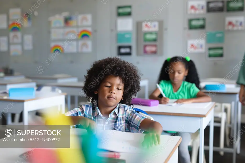 African american elementary school students studying at desk in classroom. unaltered, education, childhood, learning, studying and school concept.