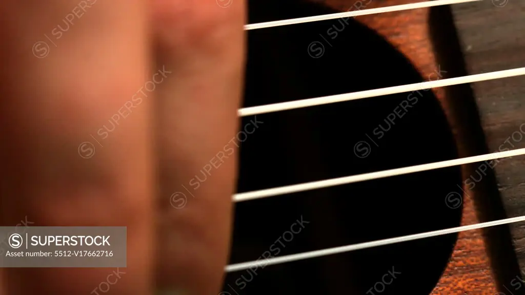 Hand strumming guitar strings close up in slow motion SuperStock