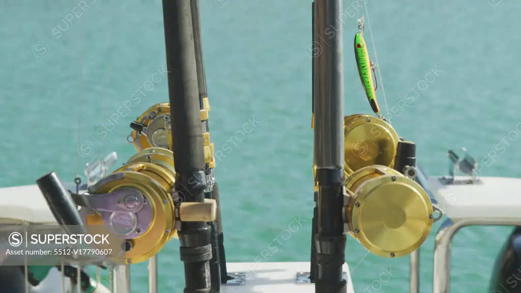 Side view close up of fishing rods standing up on a boat, ready to by used,  on a sunny day, in slow motion - SuperStock