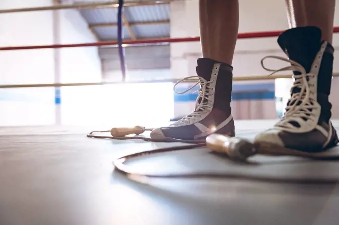 Low section of female boxer standing in boxing ring at fitness center. Strong female fighter in boxing gym training hard.