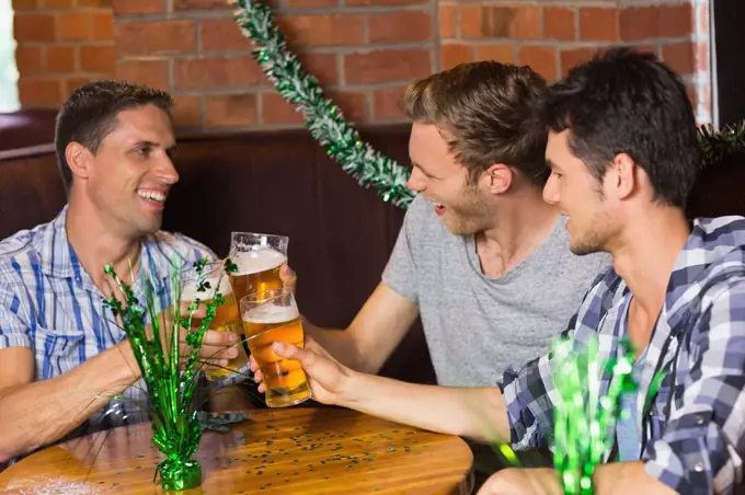 Happy friends toasting with pints of beer on patricks day in a bar