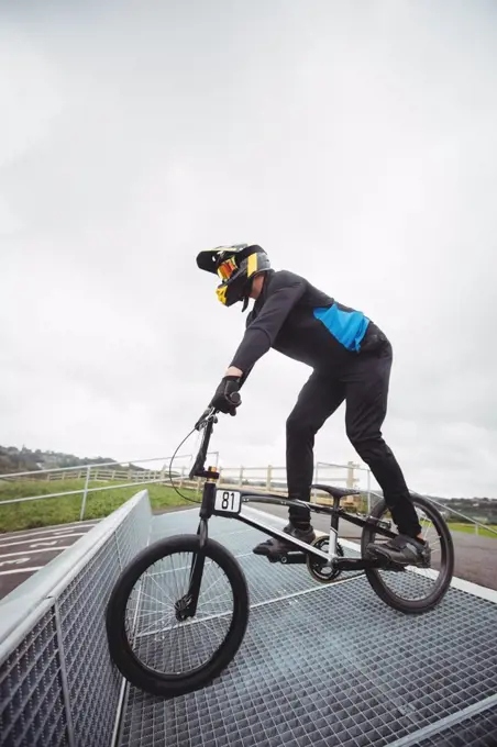 Cyclist preparing for BMX racing at starting ramp in skatepark