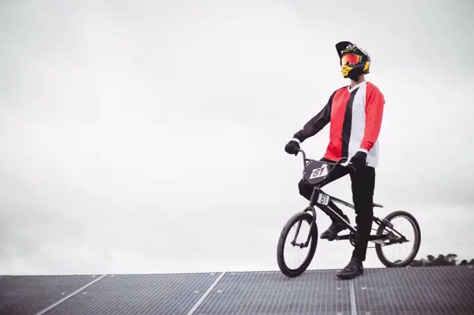 Cyclist standing with BMX bike on starting ramp at skatepark