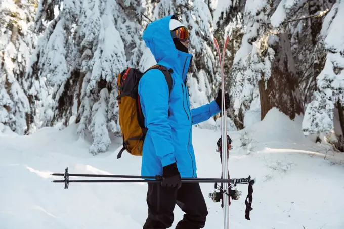 Side view of skier walking with ski on snow covered mountains