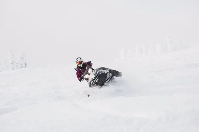 Woman riding snowmobile in snowy alps during winter